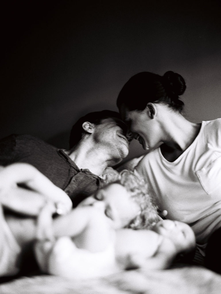 mom and dad kissing at newborn photography shoot